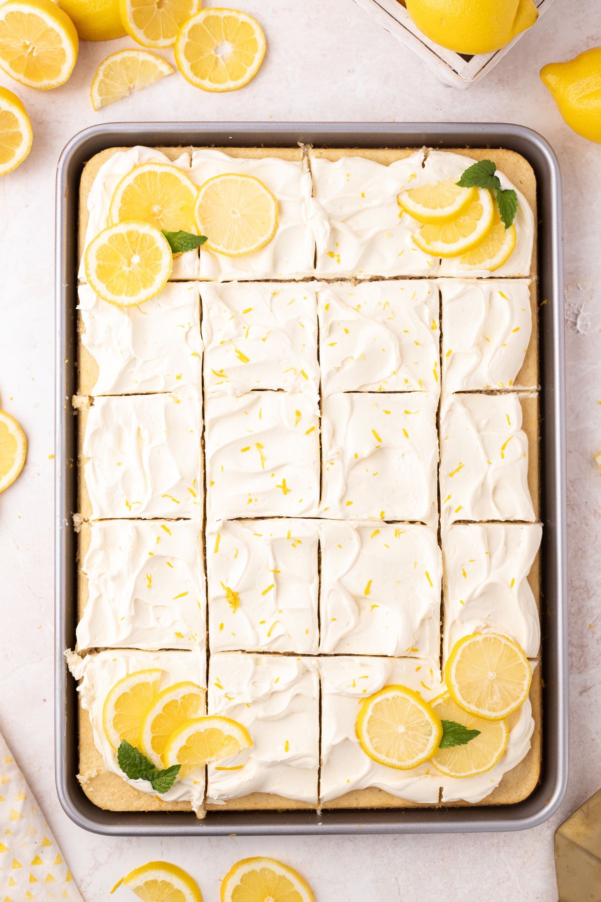 Lemon zest, lemon slices, and mint garnished on top of the cake.