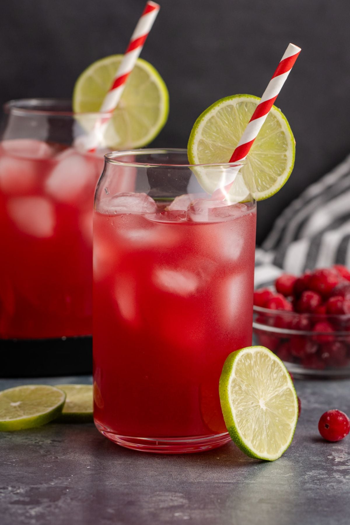 two cocktails on a table garnished with lime and a straw
