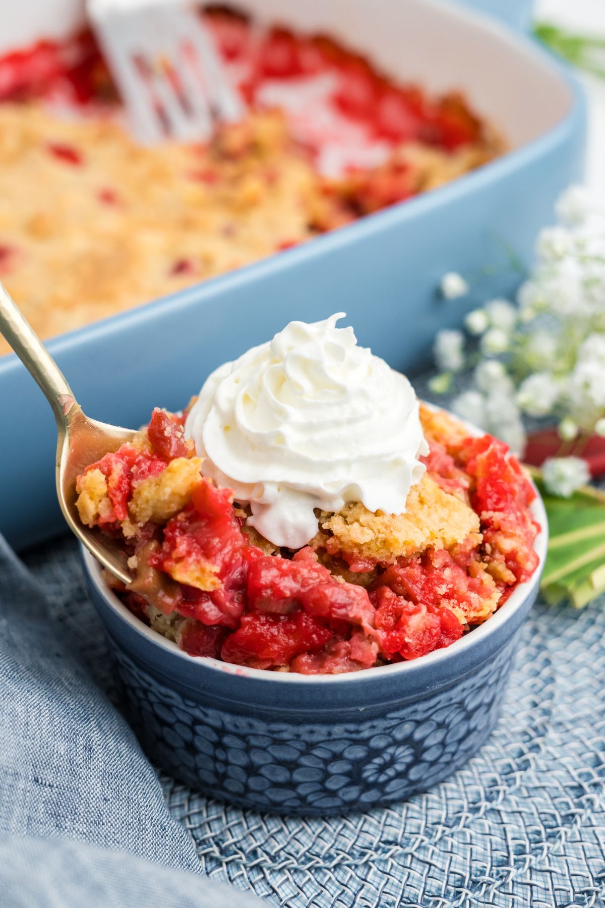 Rhubarb dump cake in a ramekin topped with whipped cream.