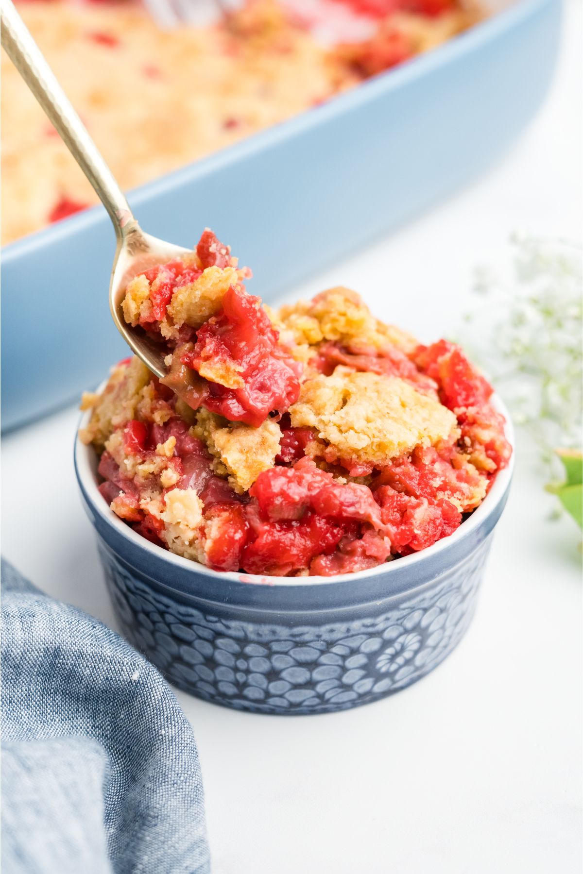 A cup of rhubarb cake with a spoon, taking some out.