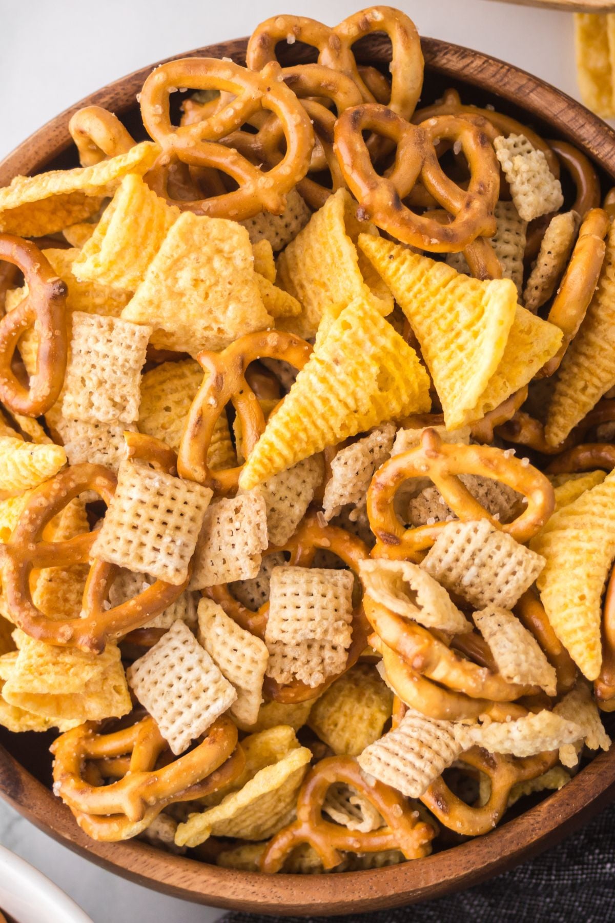 A wooden bowl full of snack mix
