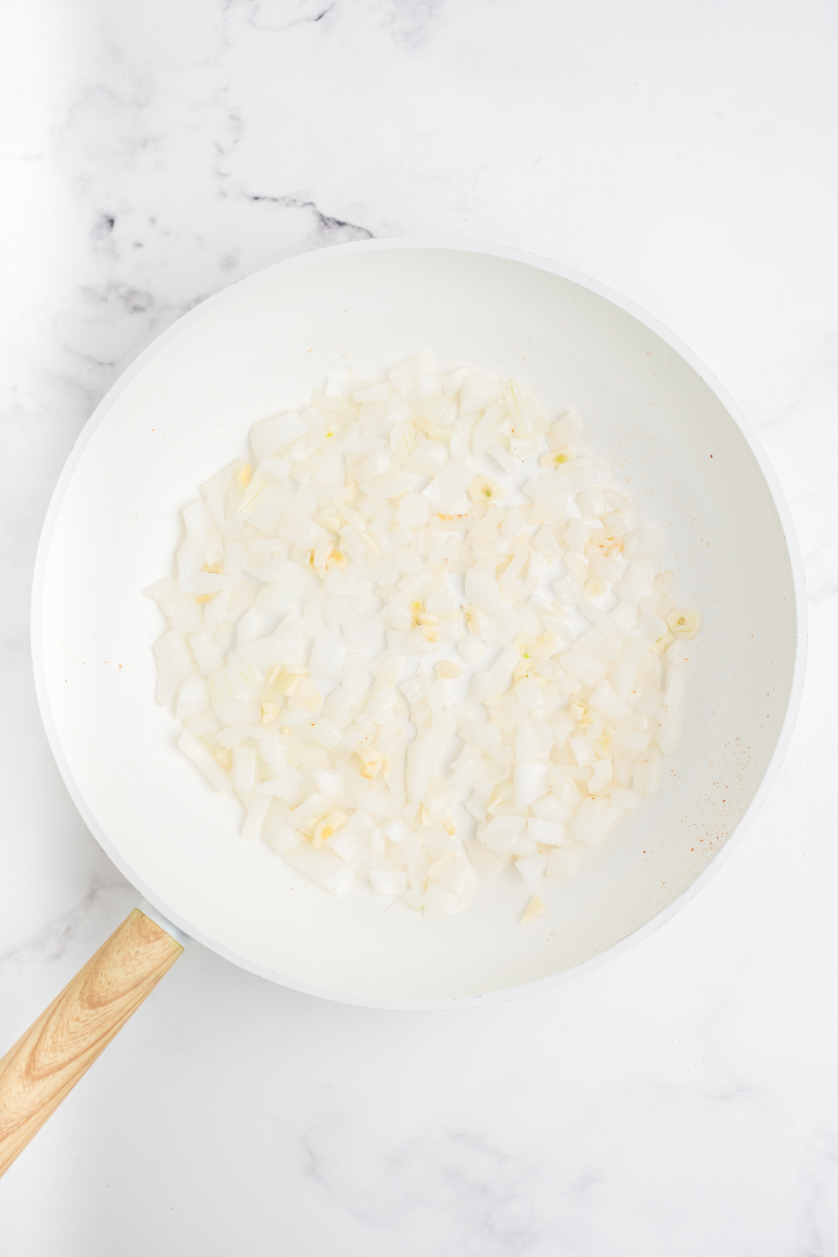 Garlic and diced onion cooking in a skillet.