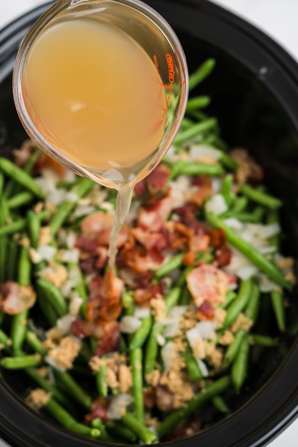 Green beans, bacon, onions, garlic, and seasoning added to the crockpot.