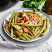 A plate full of crockpot green beans with bacon.