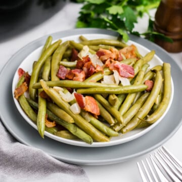 A plate full of crockpot green beans with bacon.