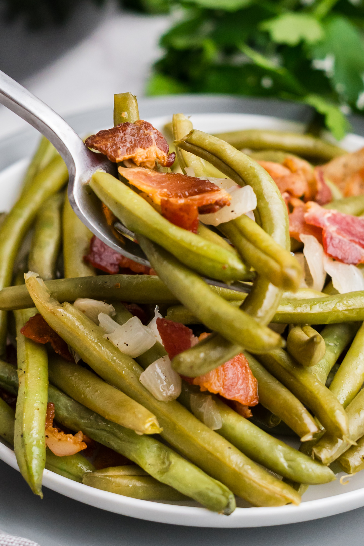 A bite of slow cooker green beans and bacon on a fork.