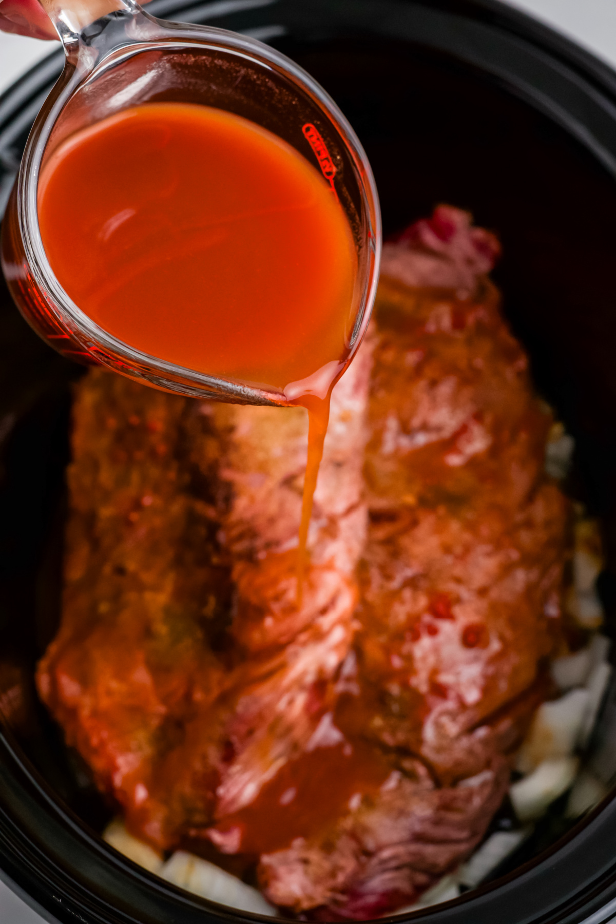 Broth, tomato paste, Worcestershire, and vinegar in a small bowl pouring over the steak in the slow cooker.
