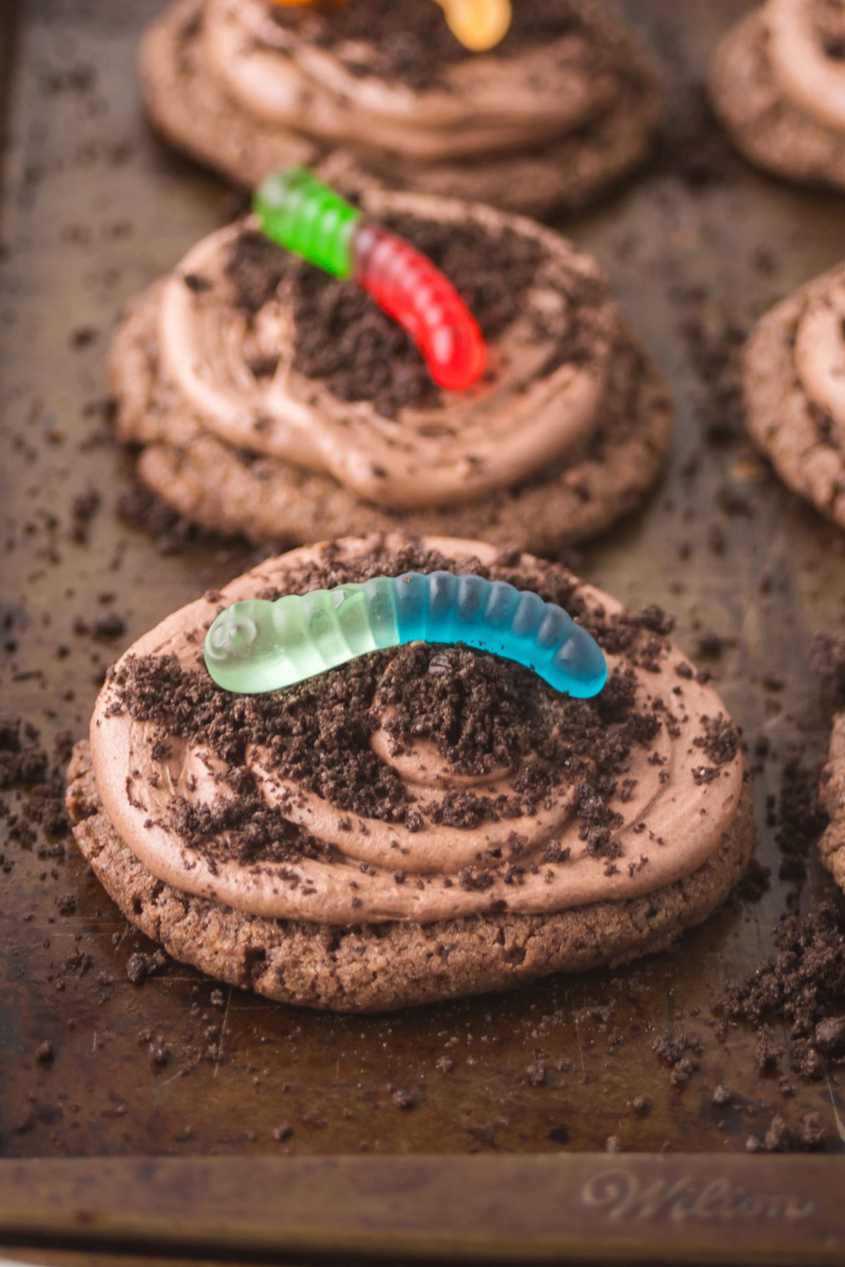 A cookie with oreo topping and a gummy worm.