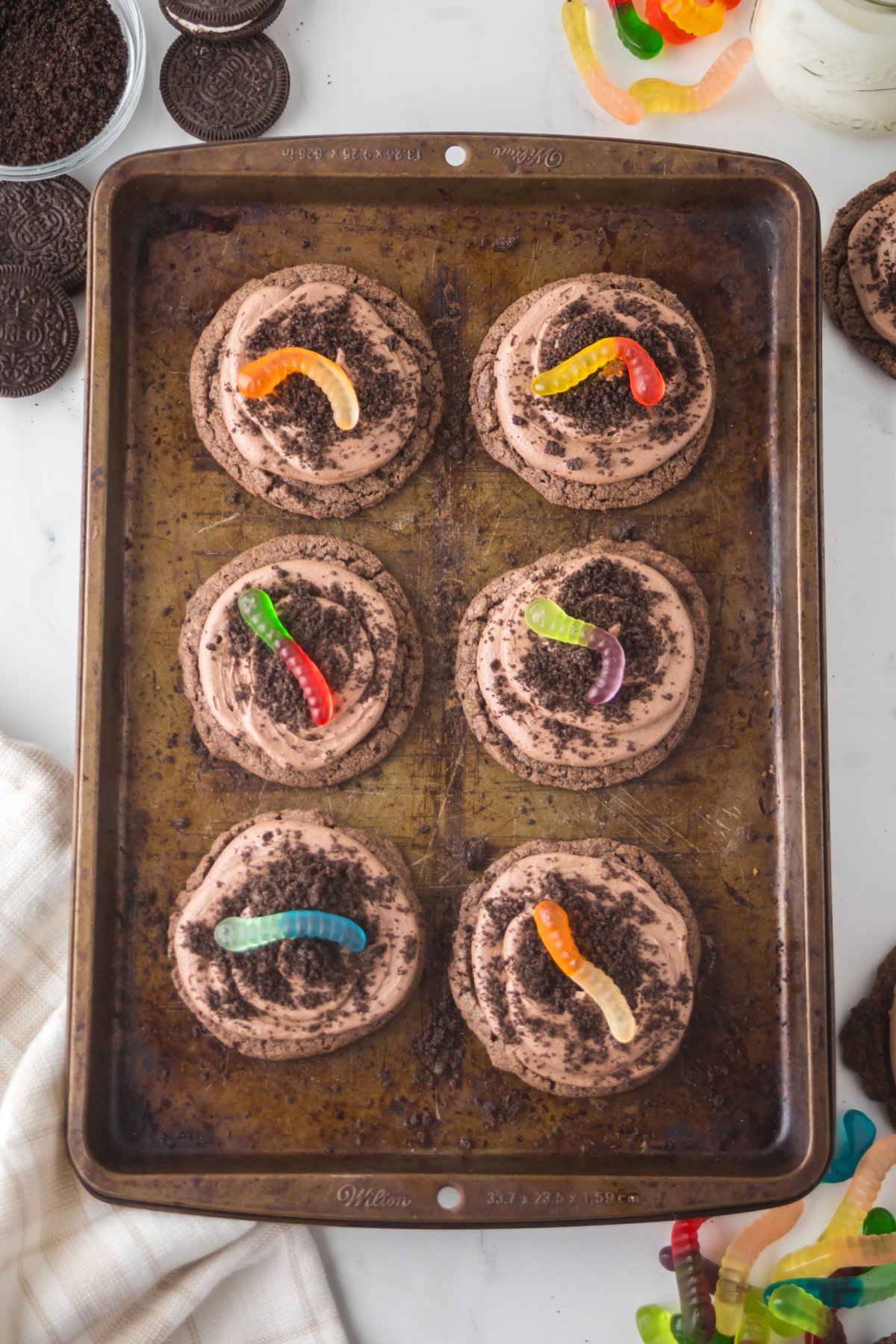 Cookies decorated with crushed oreos, and a gummy worm.