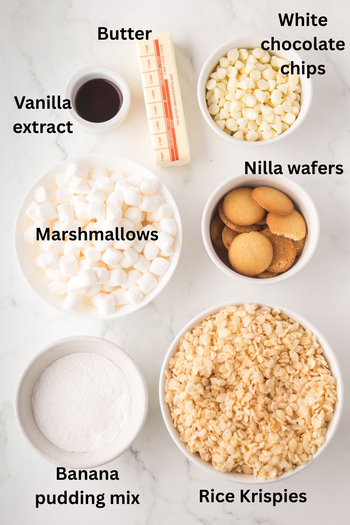 Ingredients to make banana rice krispie treats in bowls on the table with labels to identify each one.
