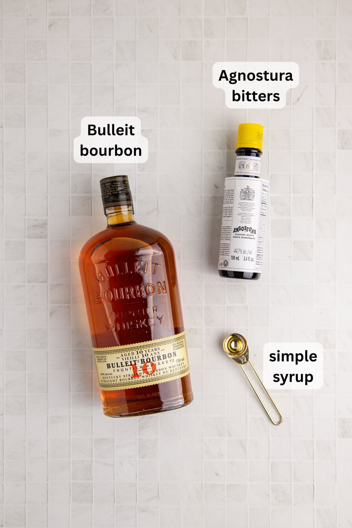 Ingredients needed to make a Bulleit Old Fashioned cocktail on table