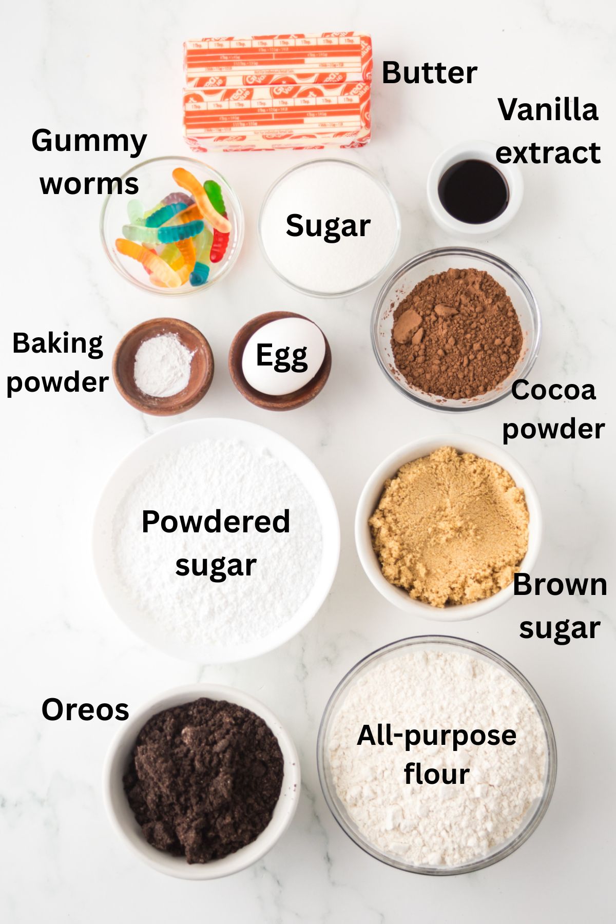 Ingredients on the table to make dirt cake cookies with text labels on them to identify each one.