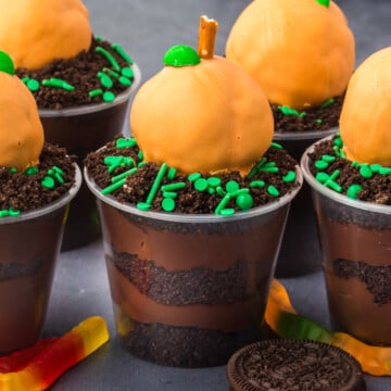 Pumpkin dirt cups with an Oreo cookie on the side and gummy worm.