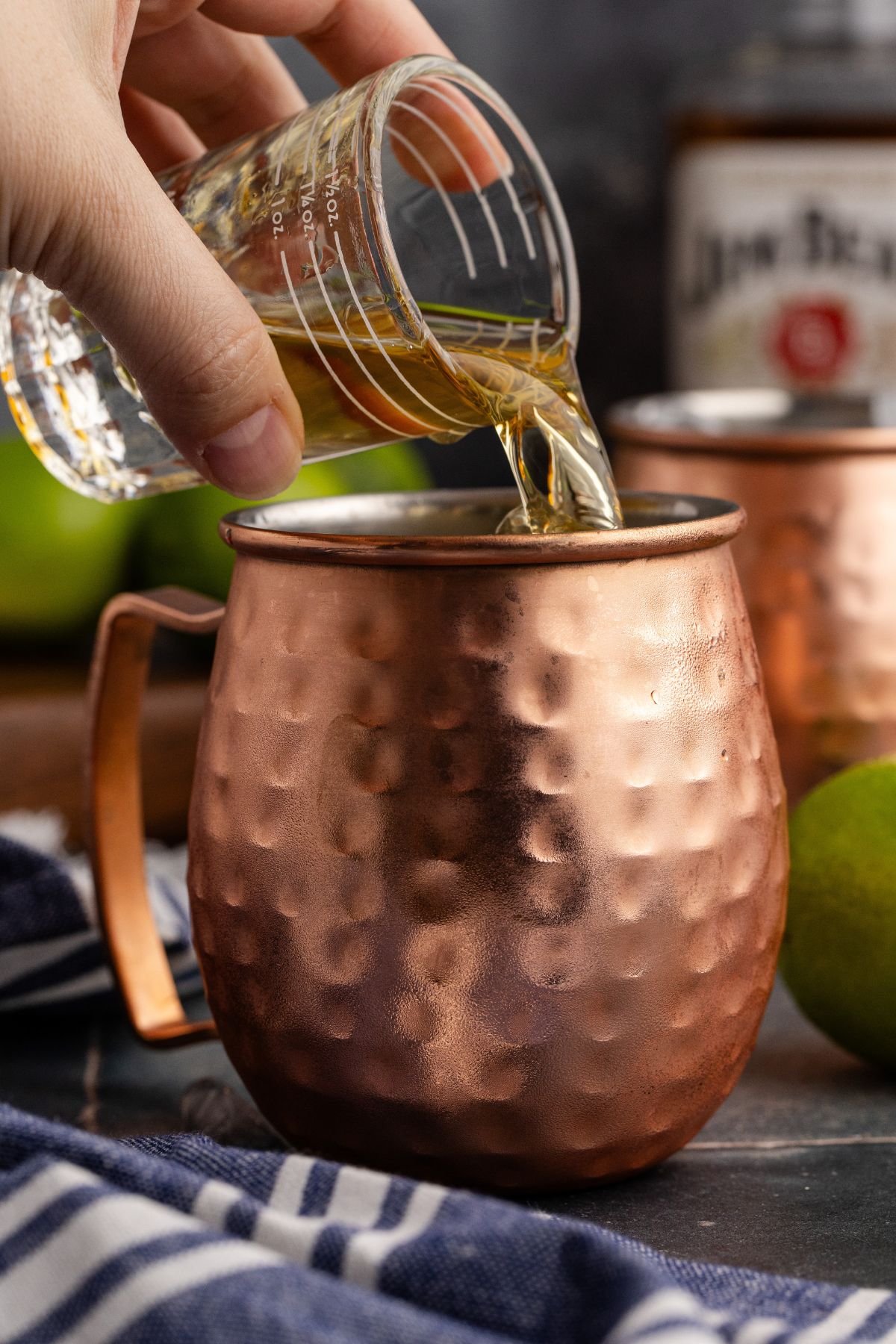 A mug about ¾ full of ice, with lime juice and bourbon being added.