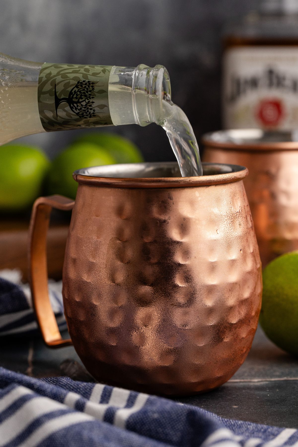 Ginger beer being added, stirred and garnished with mint.