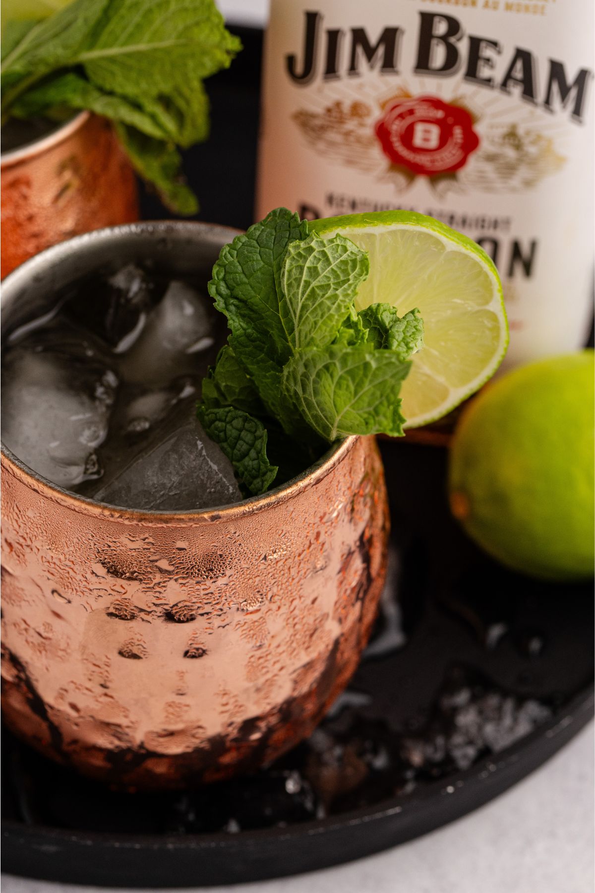 A bottle and cocktails on a table ganished and ready to drin,
