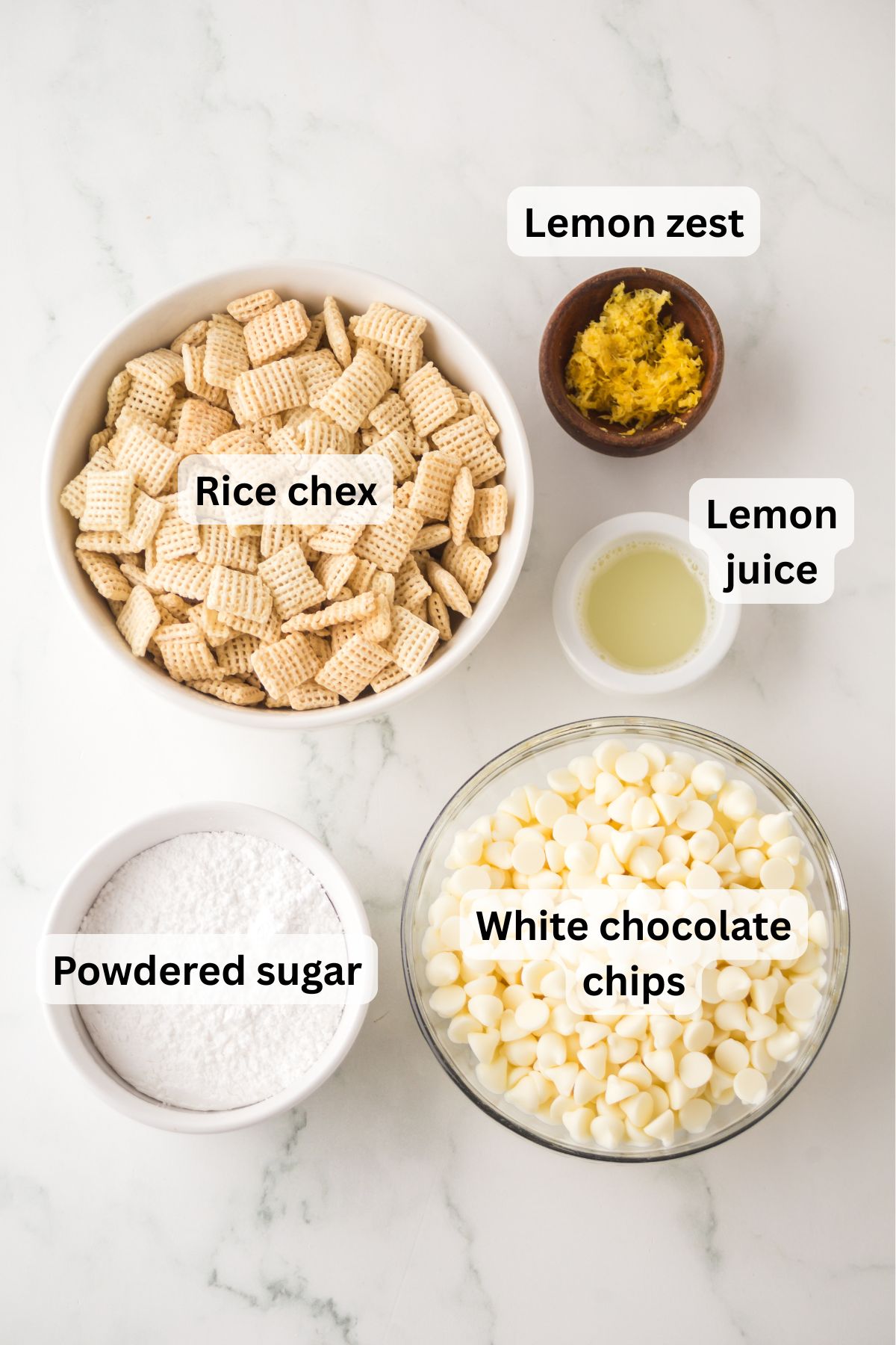 The ingredients needed to make lemon Chex mix in bowls on the table with labels to identify each one.