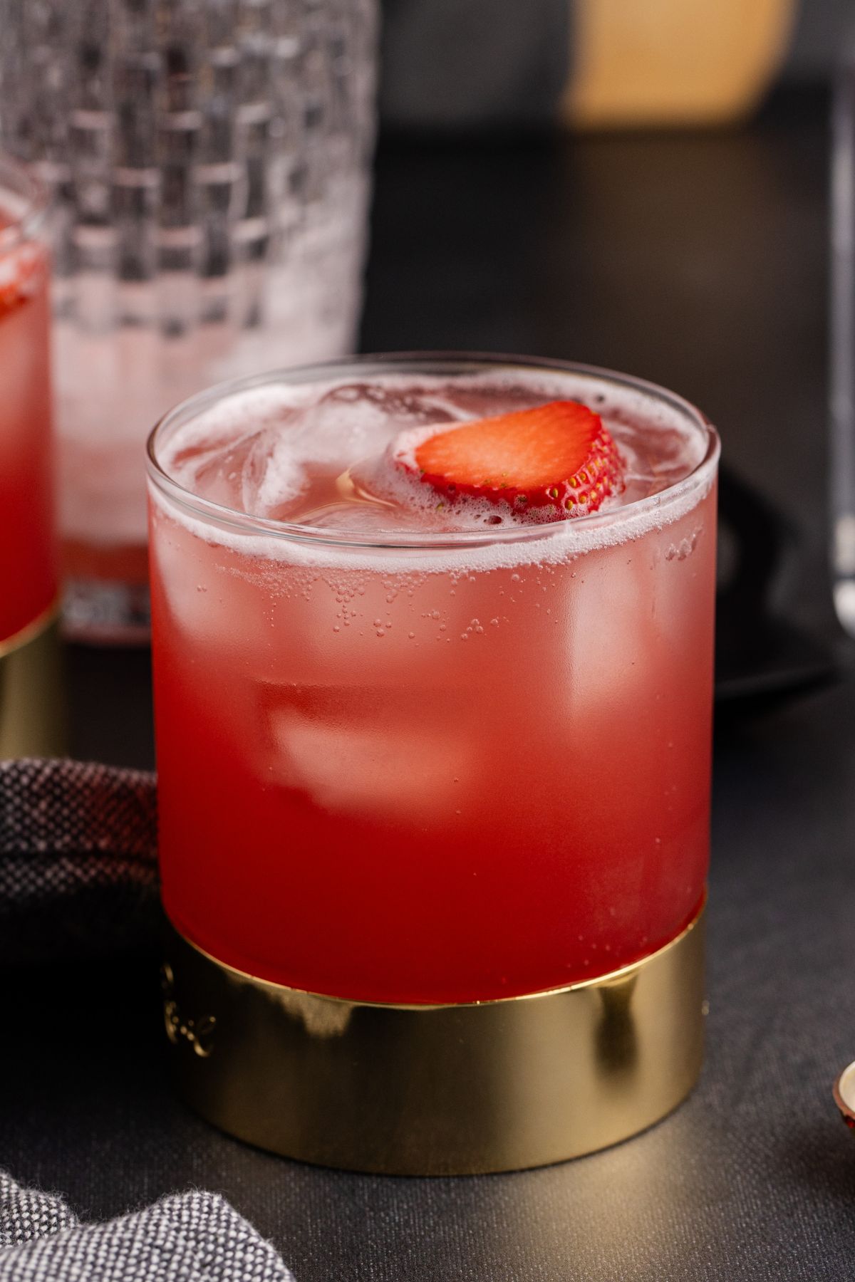 Cocktail on a table with shaker in the background.