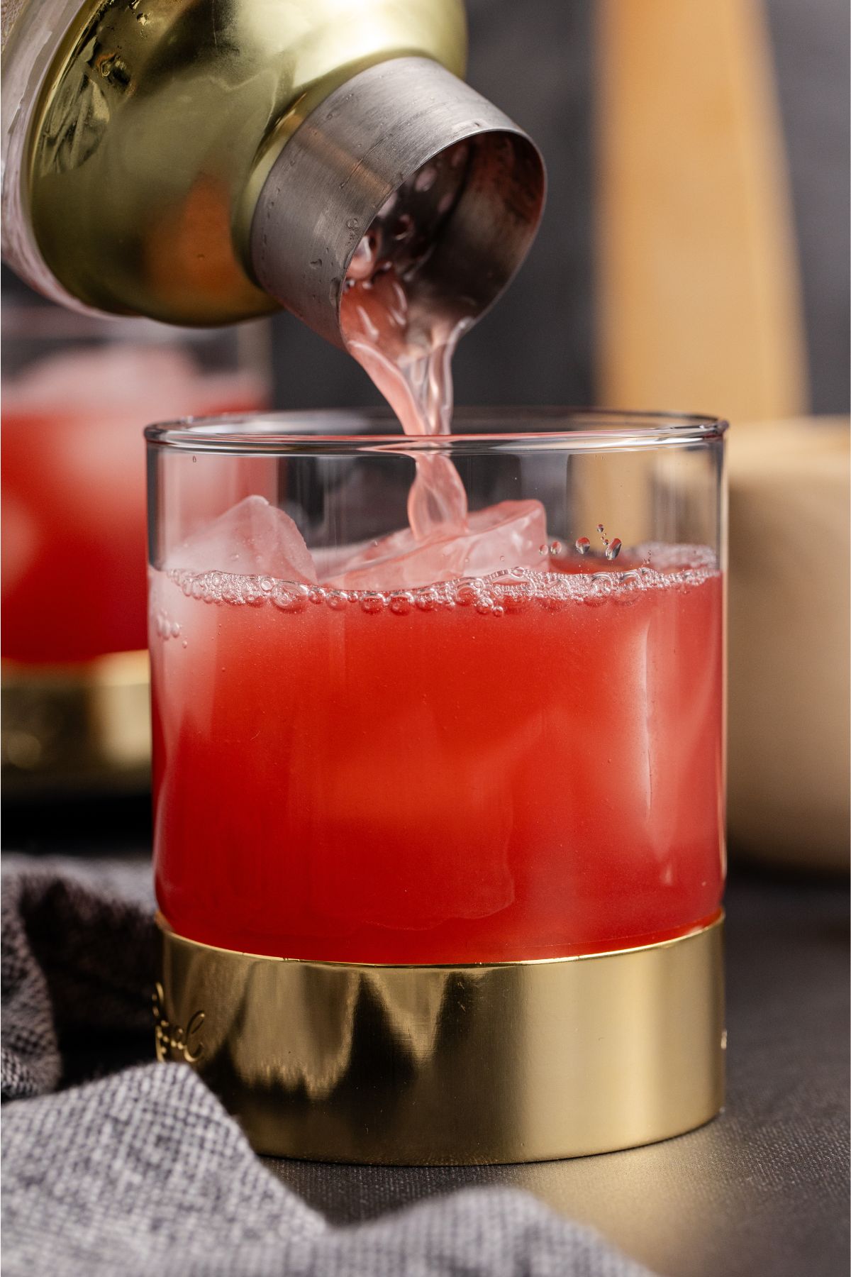 Shaken cocktail being poured into glass for serving.