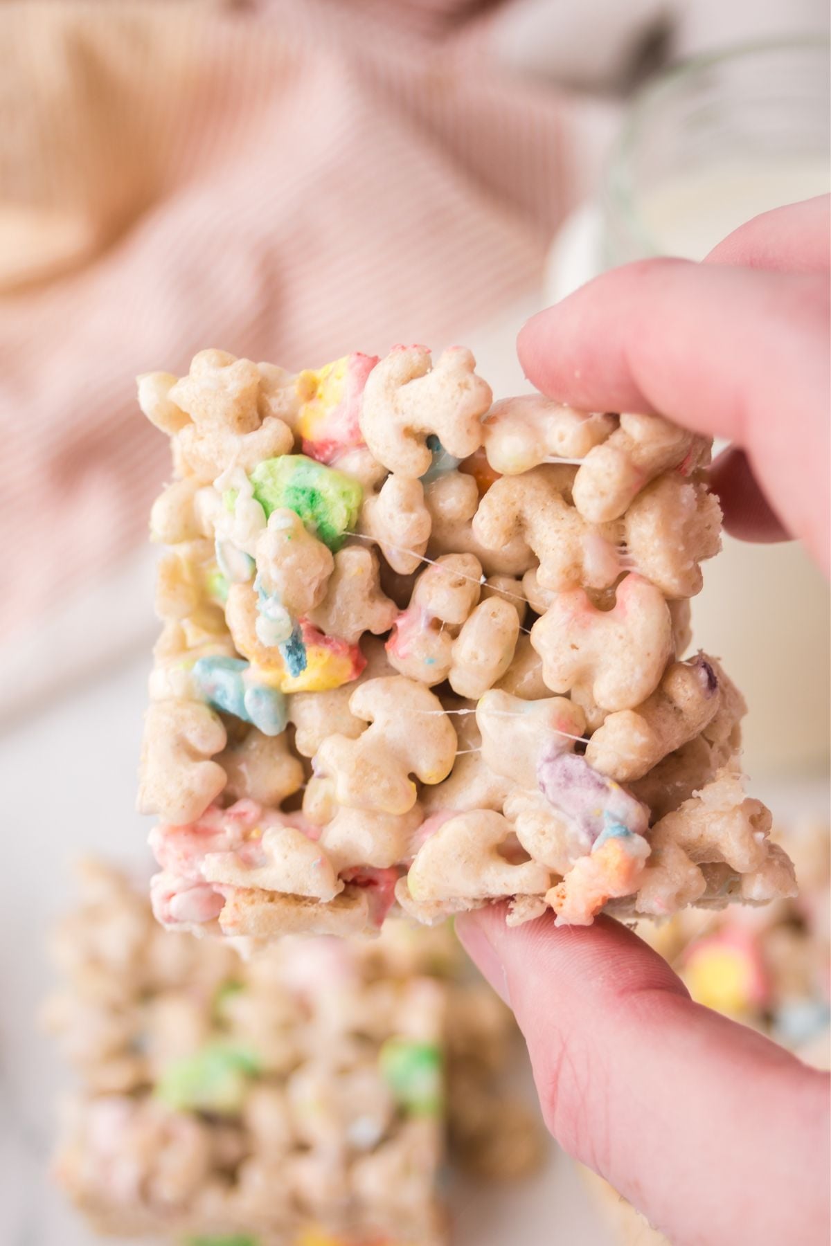 A rice krispie treat being held up in the air.