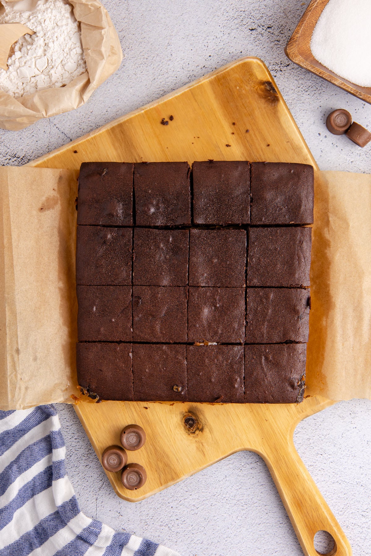Brownies cooked and cut into squares on a cutting board.