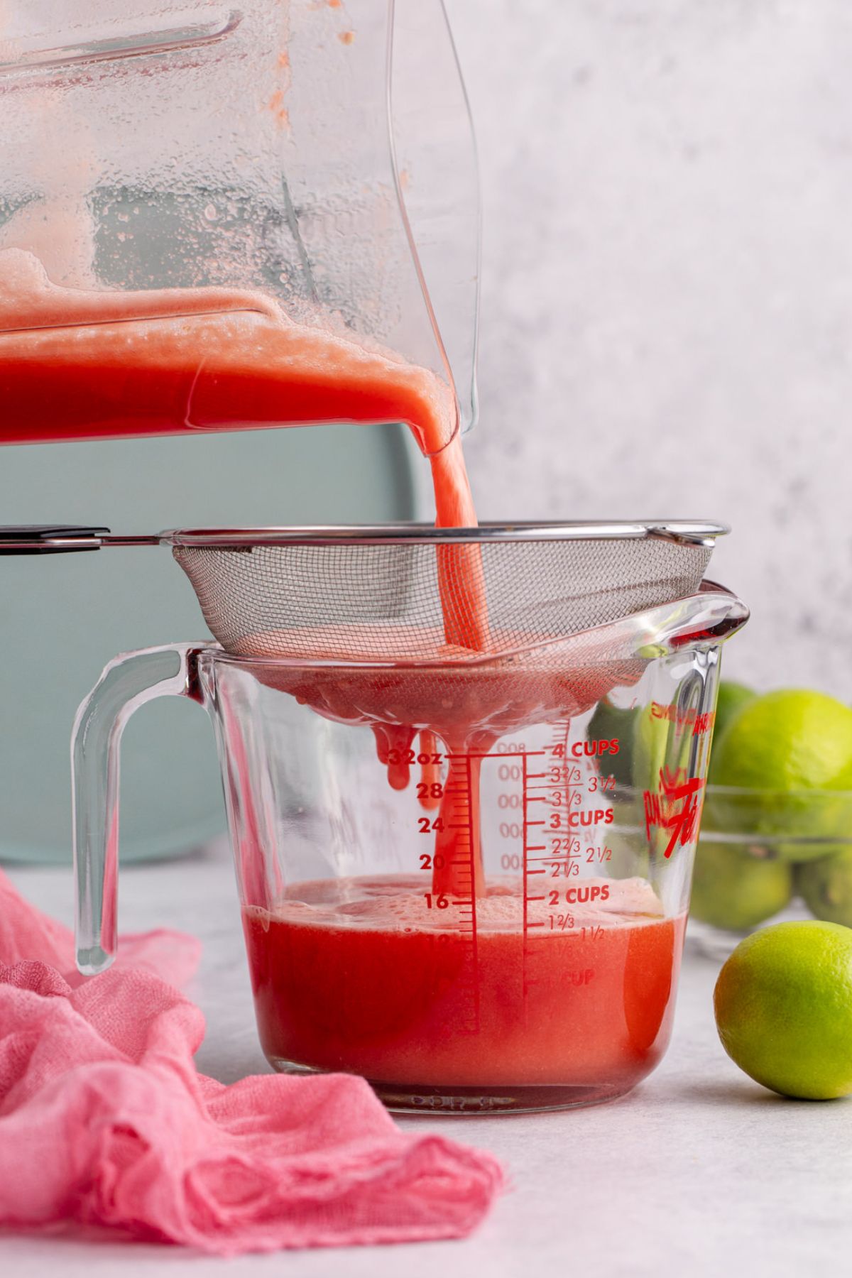 Blended watermelon being strained into measuring cup.
