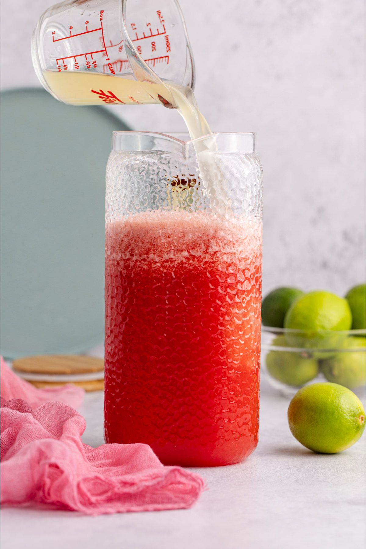Vodka and lime juice being added to pitcher.