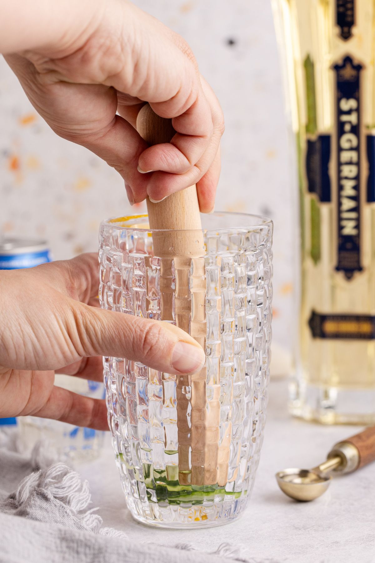 Cucumber being muddled in shaker.