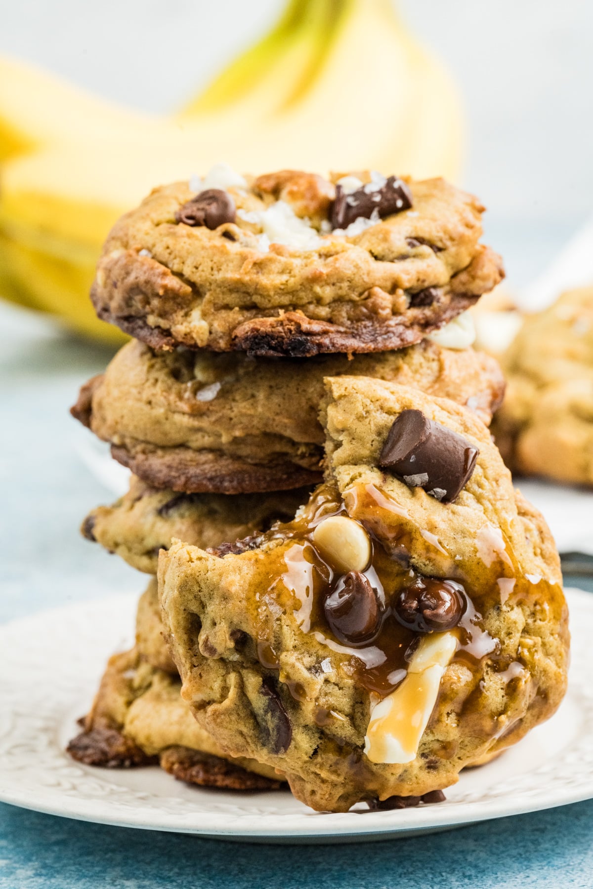 A stack of banana cookies with one bitten off, with caramel running down the side.