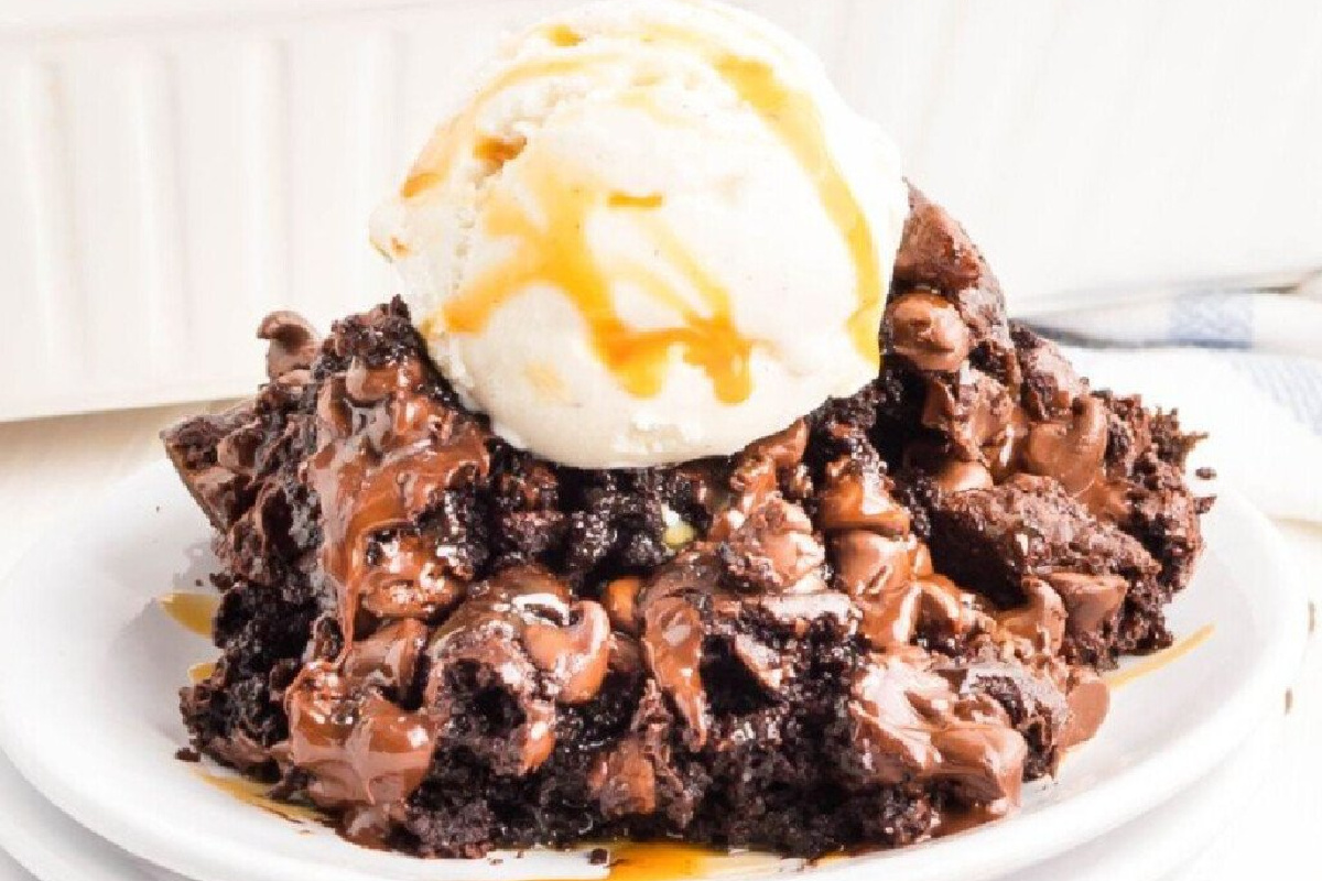 A scoop of pudding cake on plate with scoop of ice cream.