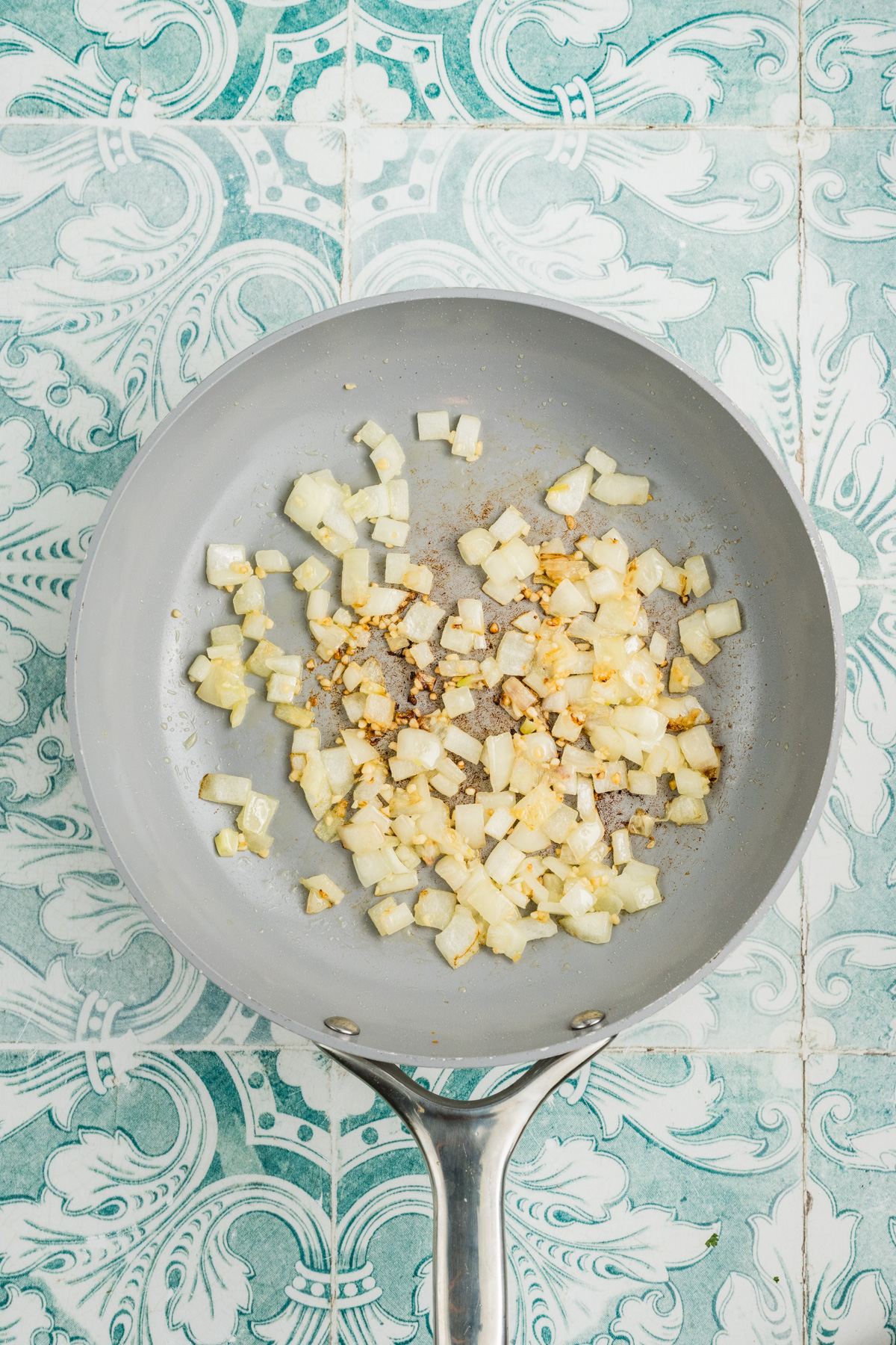 Onion and garlic in a fry pan being sauteed.