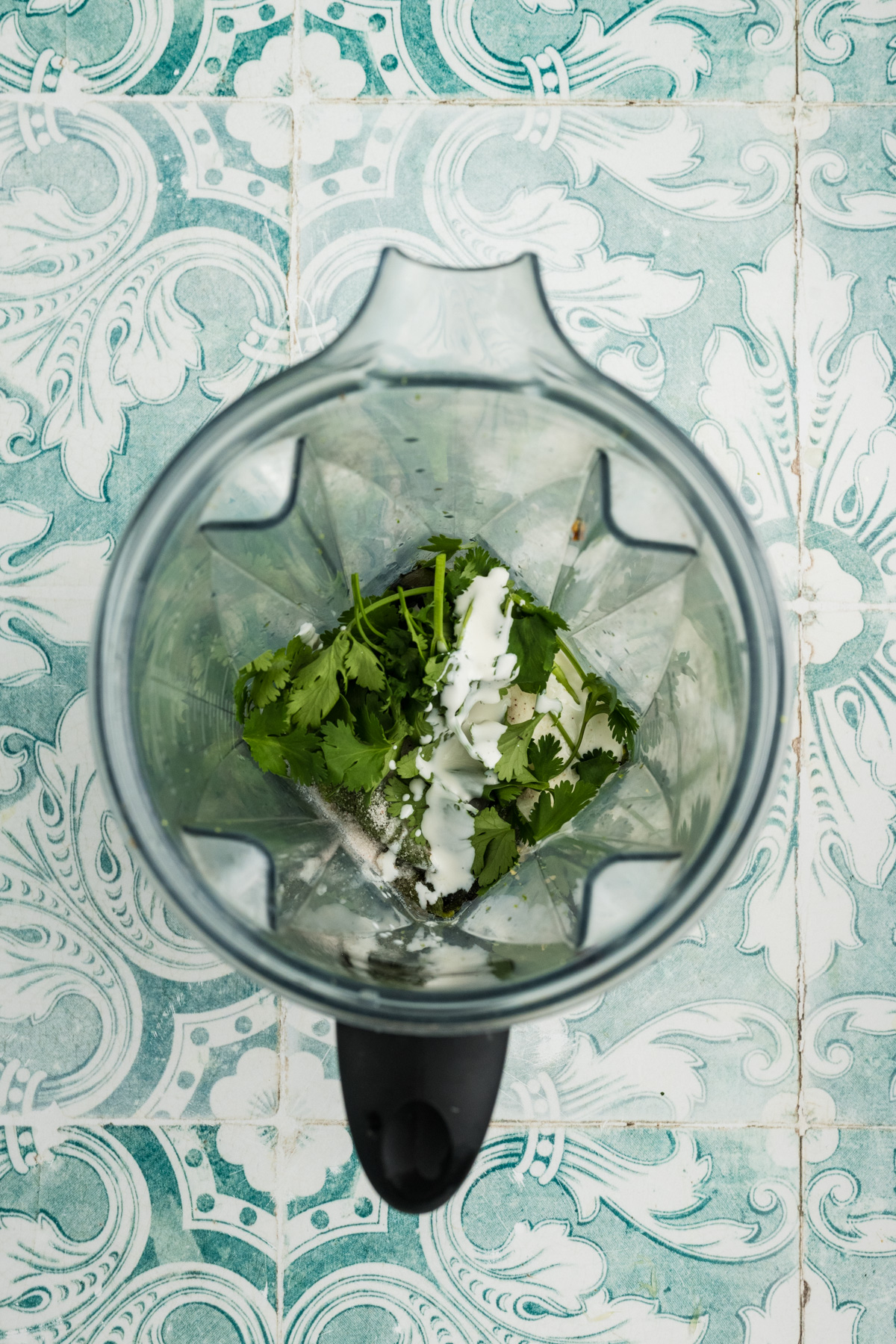 A blender full of onions, garlic, peppers, crema and cilantro.