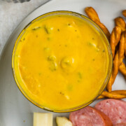 Jalapeño Mustard in a bowl on a platter with pretzels, salami slices and cheese.