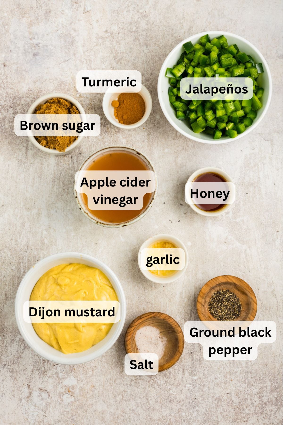 All of the ingredients needed to make Jalape&ntilde;o Mustard in bowls on a counter.