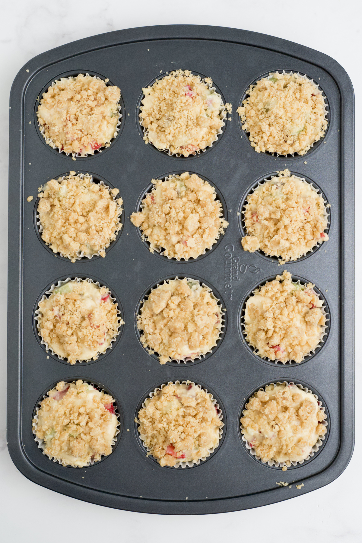 Muffin tin filled with the batter and  streusel on top.