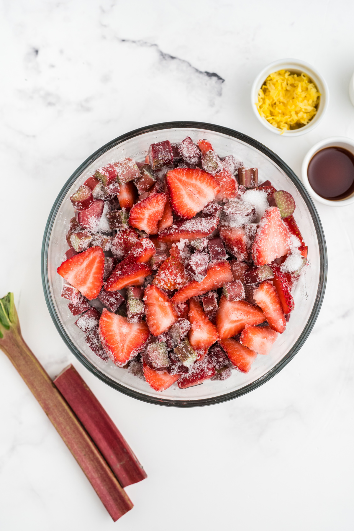 Strawberries and rhubarb added to a bowl with the other ingredients to release the juices.