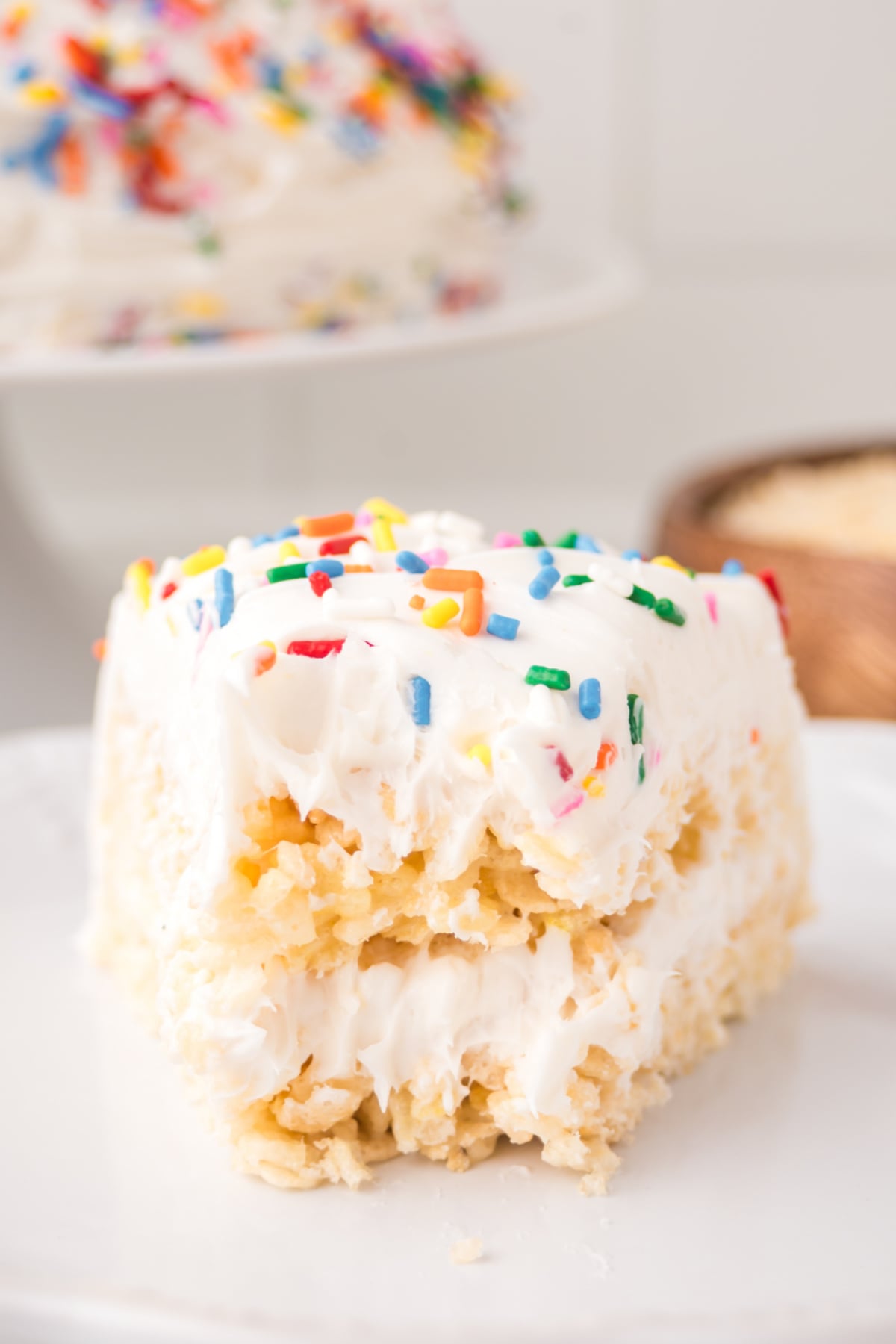 A slice of cake Rice Krispie treats on a plate missing a bite