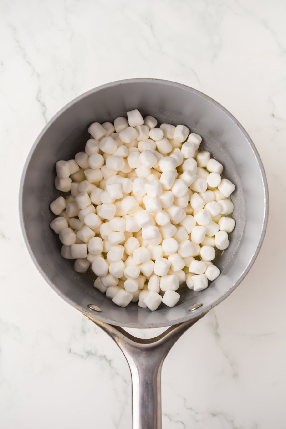 Melted butter with marshmallows added to saucepan.