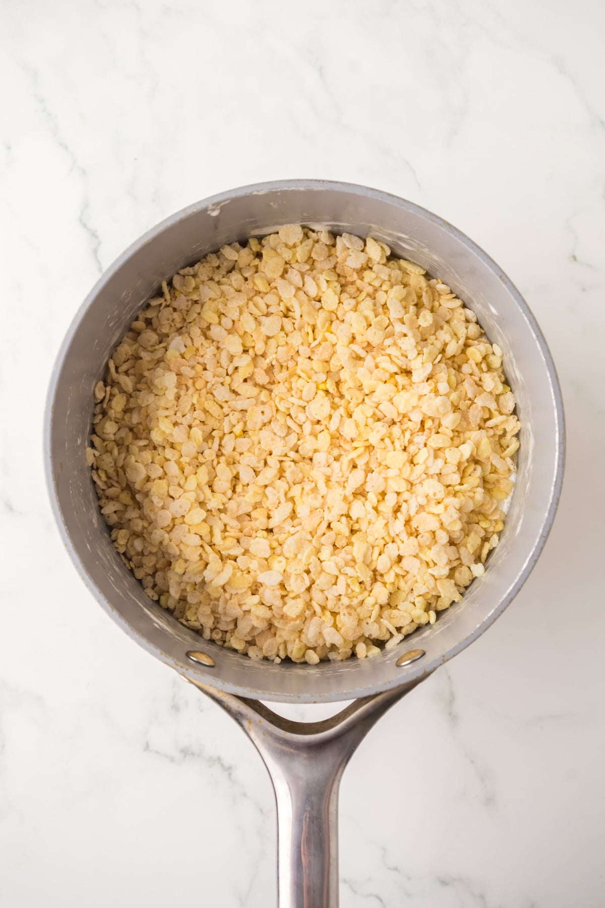 Rice Krispies added to marshmallow mixture in saucepan.