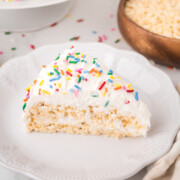 A slice of Rice Krispie Treat Cake with vanilla frosting and rainbow sprinkles