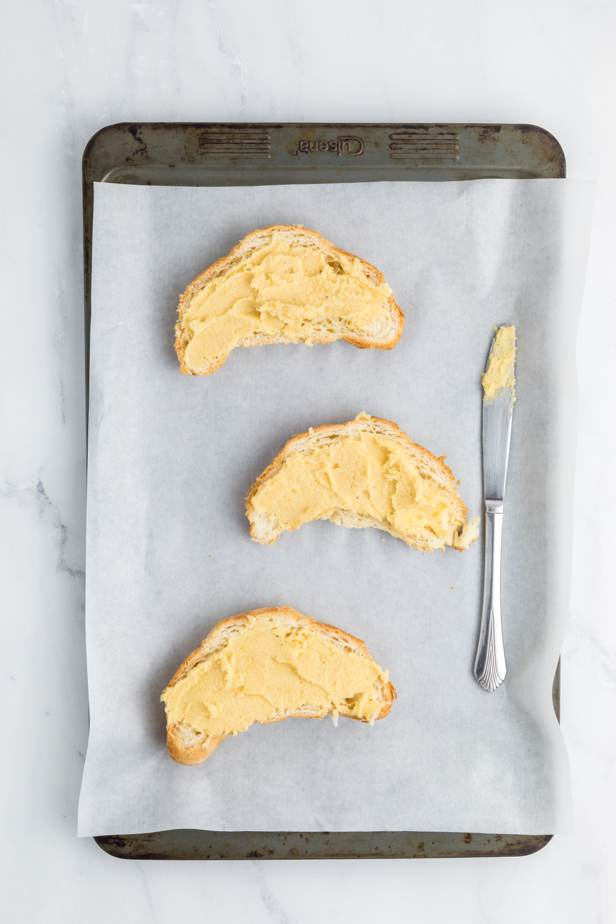 Sliced croissant cut in half and filling spread onto the bottom halves.