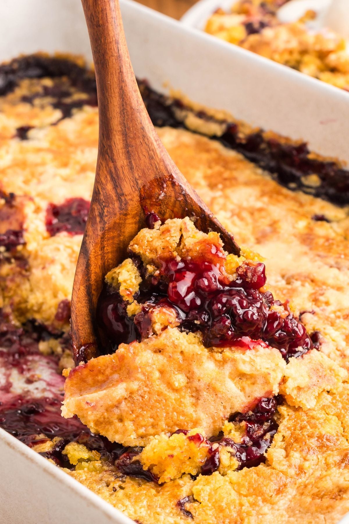 Blackberry dump cake being scooped out of a dish.