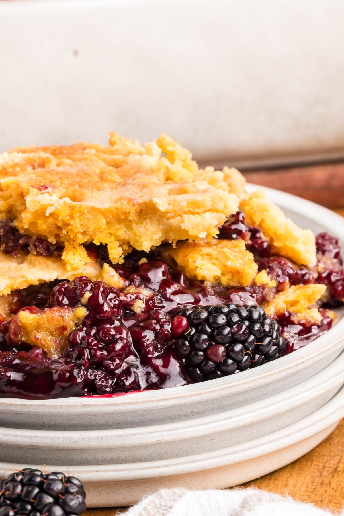 Blackberry dump cake on a stack of plates.