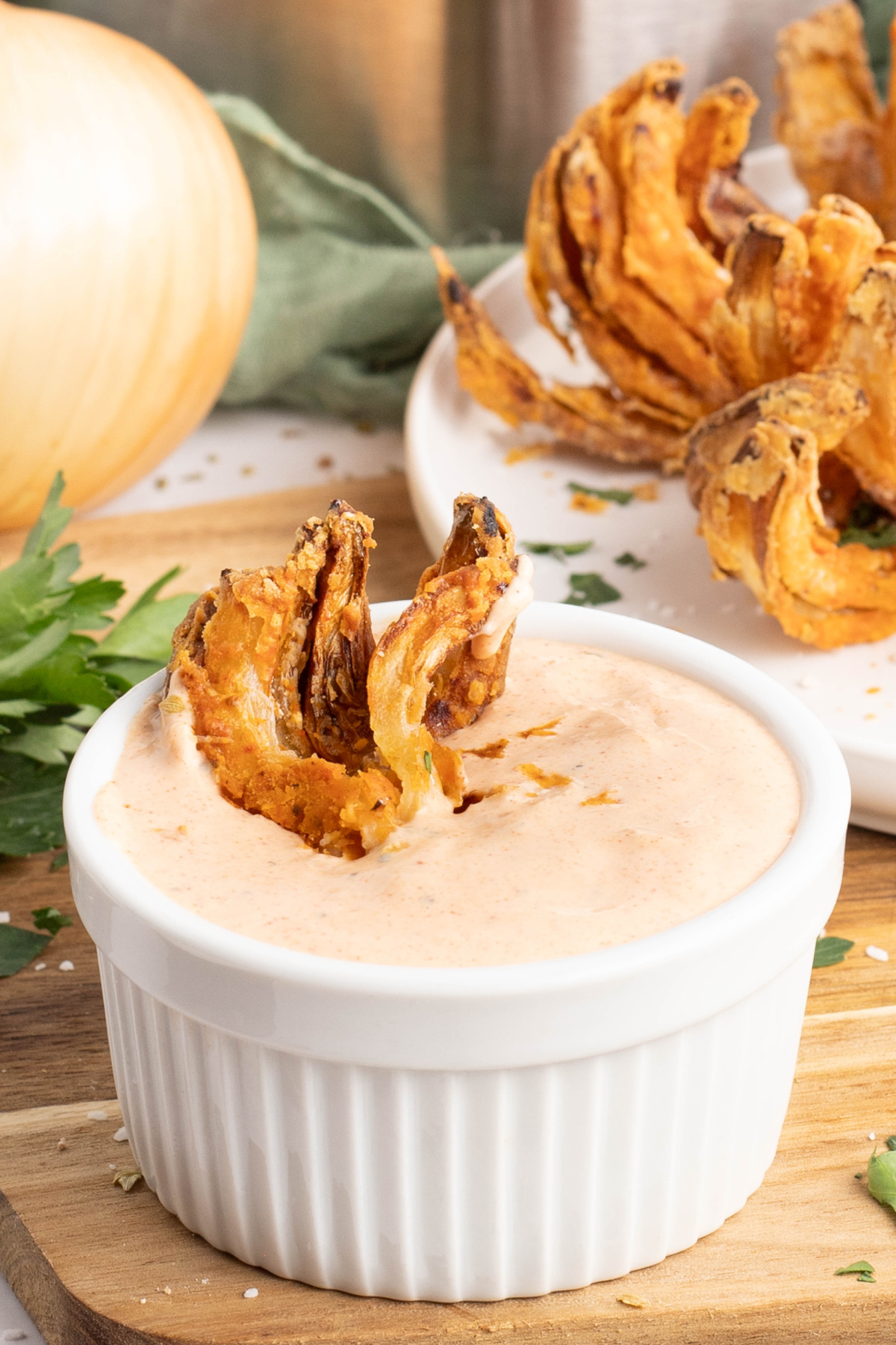 A fried onion being dipped into sauce.