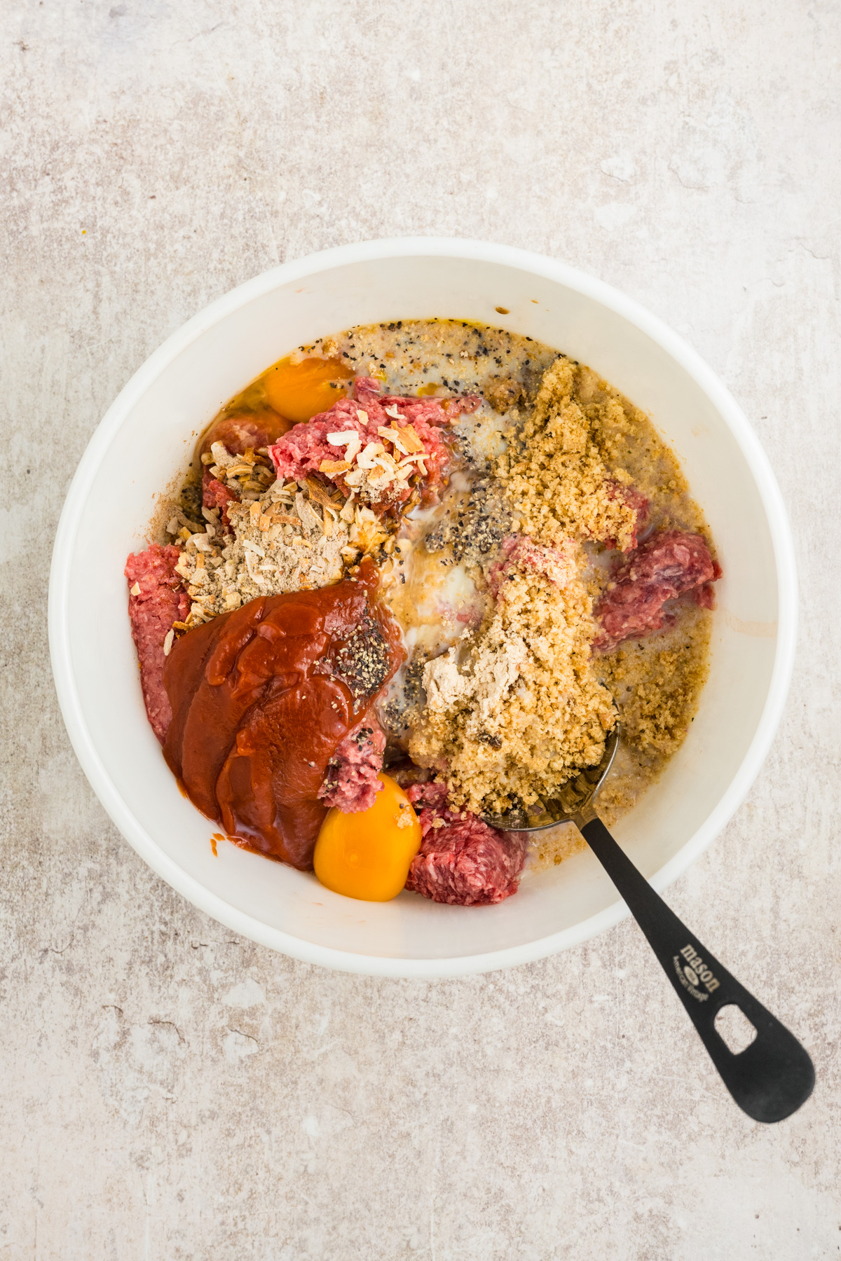 All the ingredients for the meatloaf in a mixing bowl.