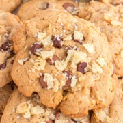 Potato chip cookies in a pile with pieces of potato chips and sea salt on top.
