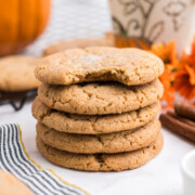 Stacked pumpkin snickerdoodle cookies with a bite taken out of the top cookie.