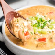 A wooden spoon scoping some slow cooker buffalo chicken chili from a bowl.