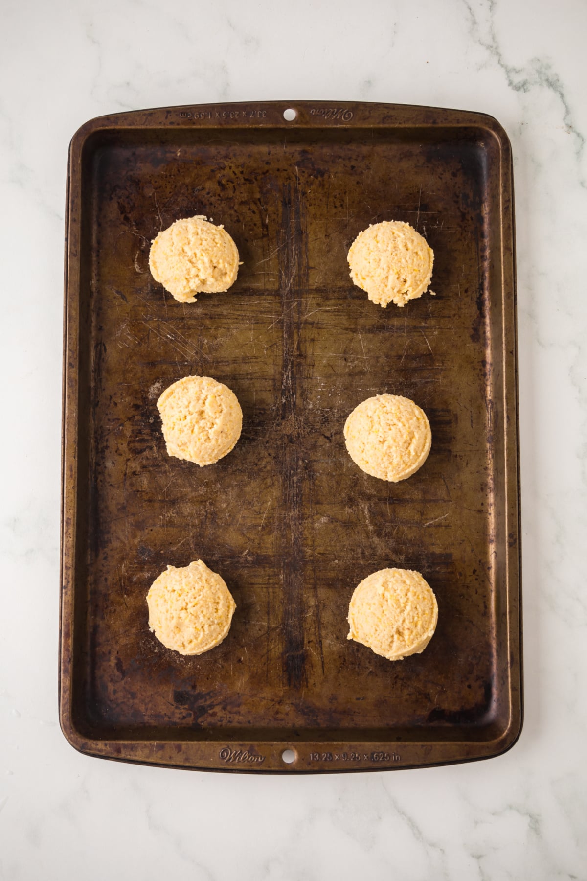 Balls of cookie dough onto a baking sheet.