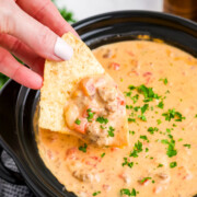 Crockpot rotel dip being scooped out with a chip.